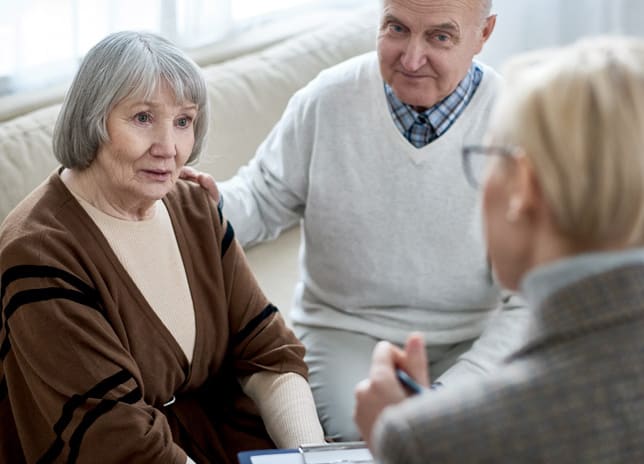 A senior couple talking with a caregiver